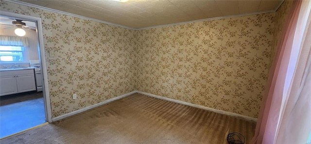 carpeted empty room featuring sink, ornamental molding, and ceiling fan