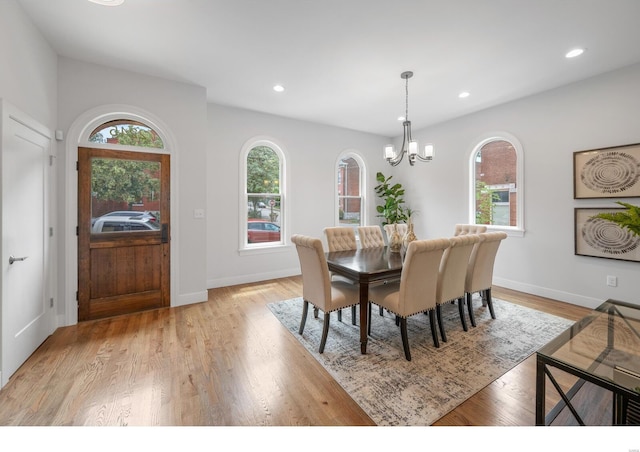 dining area with light hardwood / wood-style floors, an inviting chandelier, and a healthy amount of sunlight