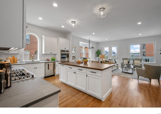 kitchen featuring backsplash, sink, appliances with stainless steel finishes, a kitchen island, and white cabinetry