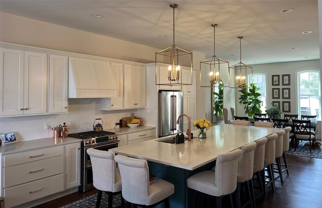 kitchen with white cabinetry, sink, a center island with sink, appliances with stainless steel finishes, and custom exhaust hood