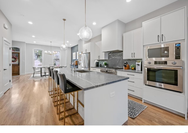 kitchen with pendant lighting, white cabinetry, an island with sink, and appliances with stainless steel finishes