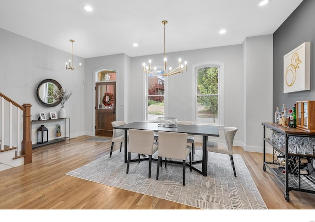 dining area with light hardwood / wood-style floors and an inviting chandelier