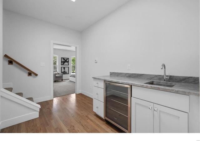 kitchen with light hardwood / wood-style floors, white cabinetry, sink, and wine cooler