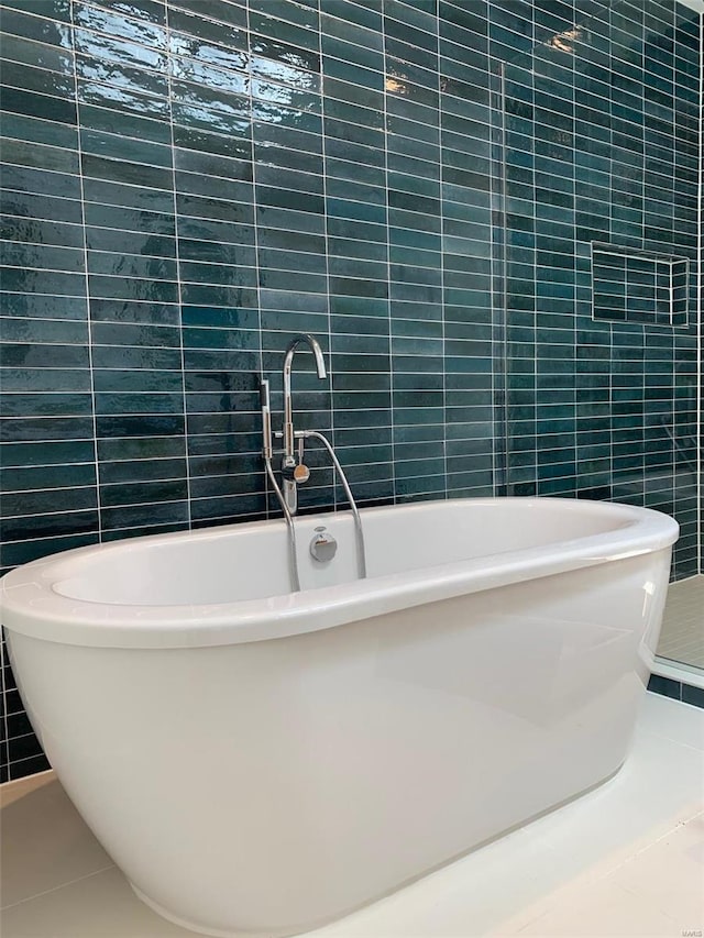 bathroom with tile patterned floors, a bath, and tile walls