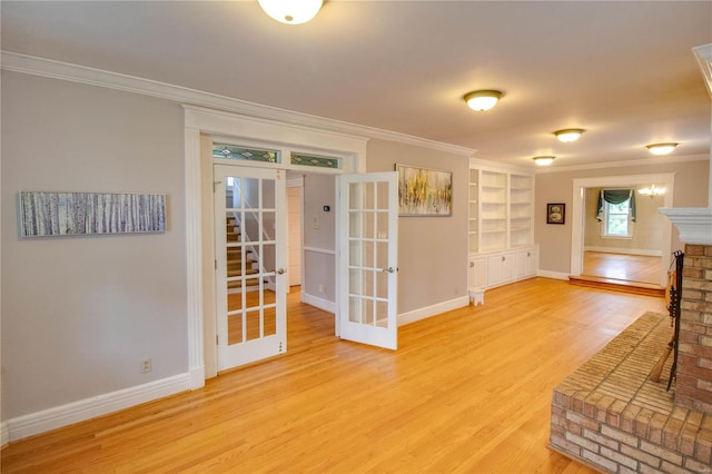 unfurnished living room featuring crown molding, wood-type flooring, a brick fireplace, built in shelves, and french doors