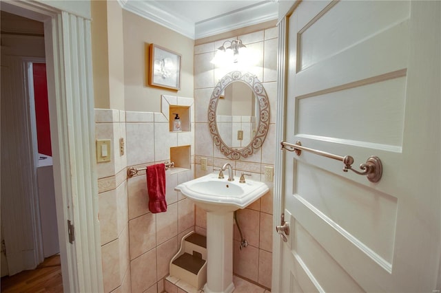 bathroom featuring ornamental molding, sink, and tile walls