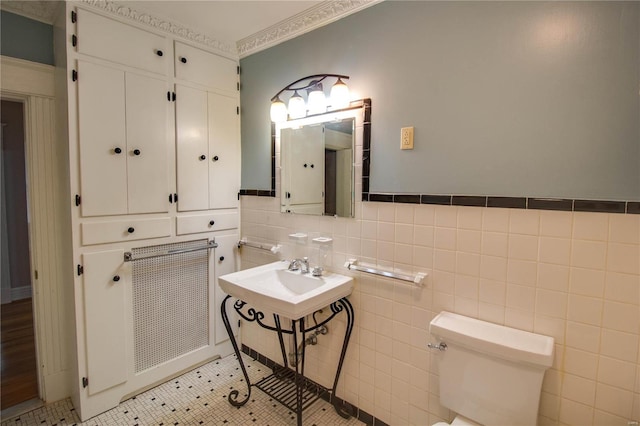 bathroom featuring tile patterned floors, toilet, sink, and tile walls