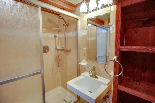 bathroom with tasteful backsplash, a shower with door, and sink