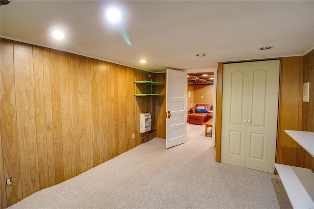 carpeted bedroom with heating unit, wooden walls, and a closet