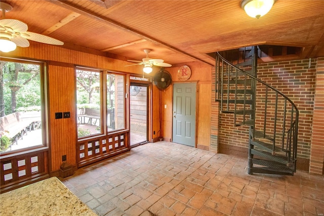 interior space with wood ceiling, ceiling fan, brick wall, and wooden walls