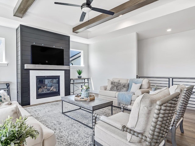 living room with beamed ceiling, ceiling fan, a fireplace, and hardwood / wood-style floors