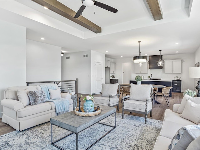 living room with sink, hardwood / wood-style flooring, beamed ceiling, and ceiling fan