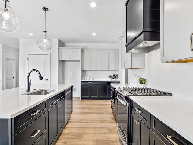 kitchen featuring sink, white cabinetry, pendant lighting, stainless steel appliances, and wall chimney range hood