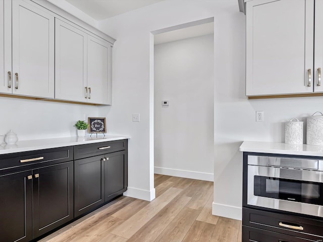 kitchen with white cabinetry, stainless steel microwave, and light hardwood / wood-style floors