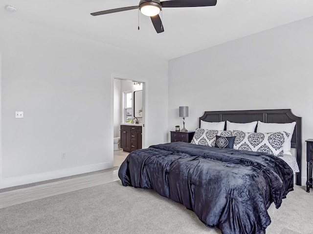 bedroom featuring connected bathroom, light colored carpet, sink, and ceiling fan