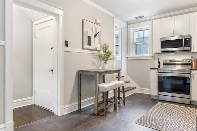 kitchen featuring stainless steel appliances, dark hardwood / wood-style flooring, white cabinets, crown molding, and backsplash