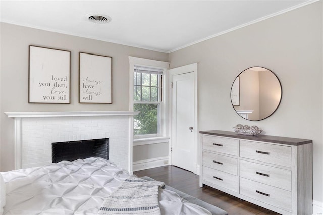 bedroom featuring crown molding, dark hardwood / wood-style flooring, and a brick fireplace