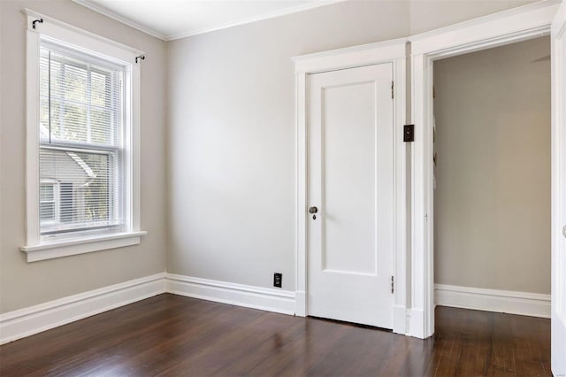 empty room featuring crown molding and dark wood-type flooring