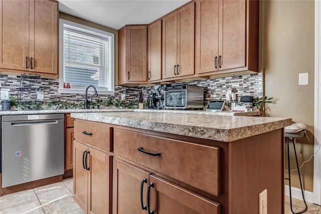 kitchen with tasteful backsplash, a breakfast bar, light tile patterned floors, and stainless steel dishwasher