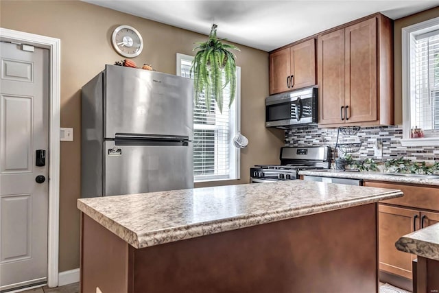 kitchen with decorative backsplash, appliances with stainless steel finishes, a center island, and sink