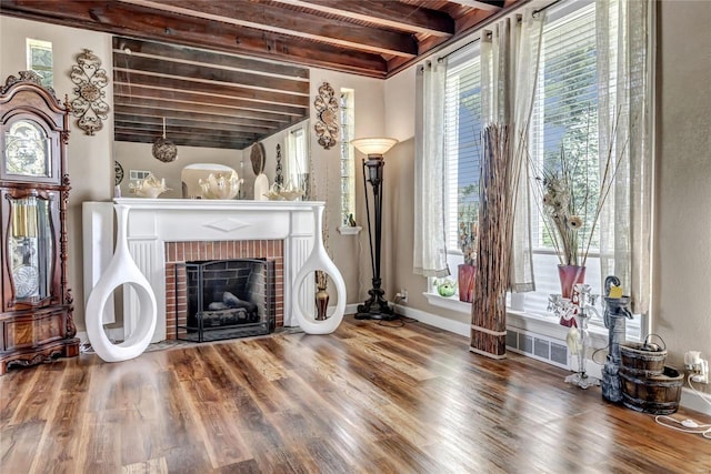 living room featuring a fireplace, beamed ceiling, and wood-type flooring