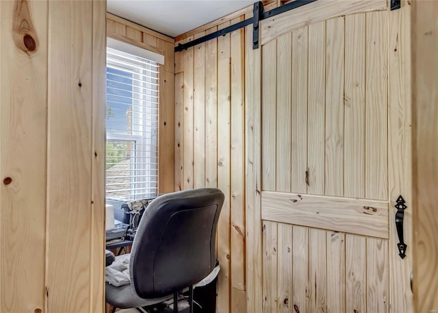 home office featuring a barn door and wooden walls