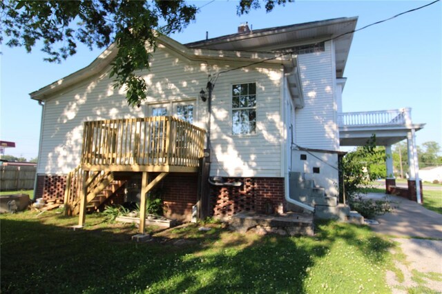 back of property featuring a wooden deck and a lawn