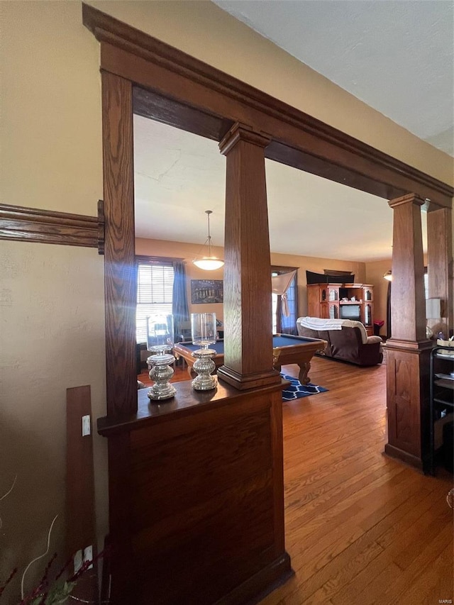 hallway featuring hardwood / wood-style floors and decorative columns