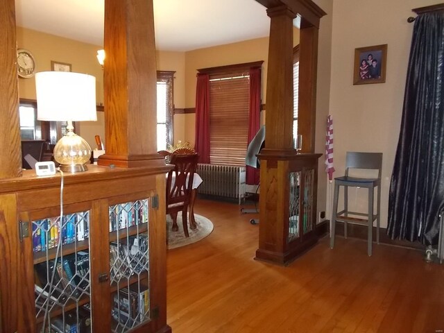 interior space with ornate columns, hardwood / wood-style floors, and radiator heating unit