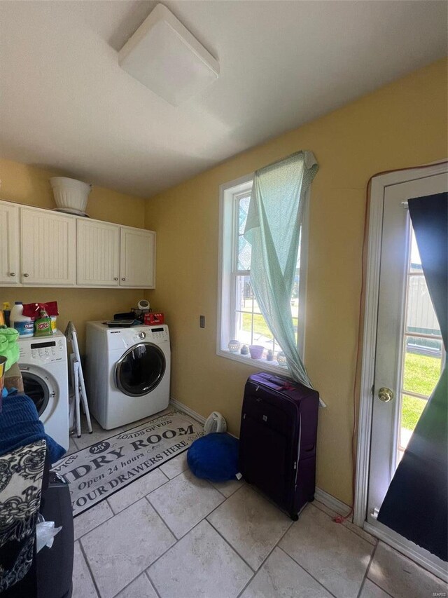 washroom with washing machine and clothes dryer, light tile flooring, and cabinets