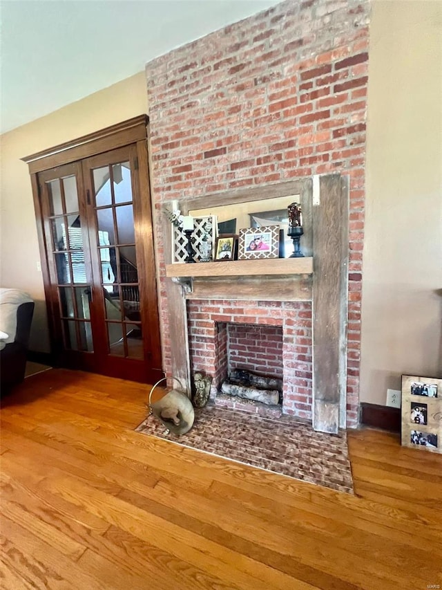 unfurnished living room with a brick fireplace, hardwood / wood-style flooring, and french doors