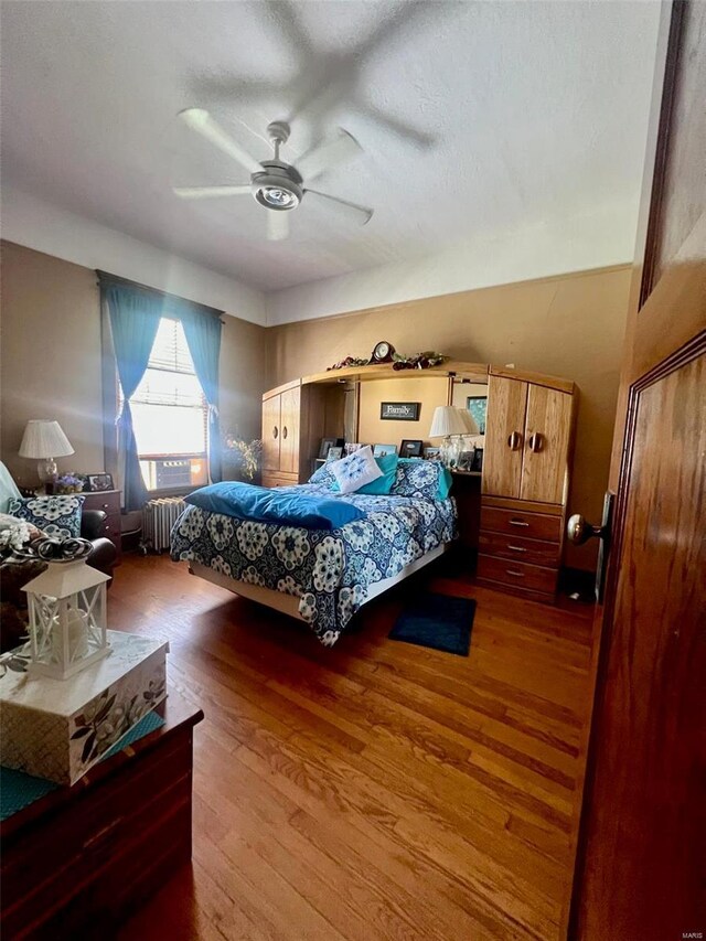 bedroom featuring ceiling fan, radiator heating unit, and wood-type flooring