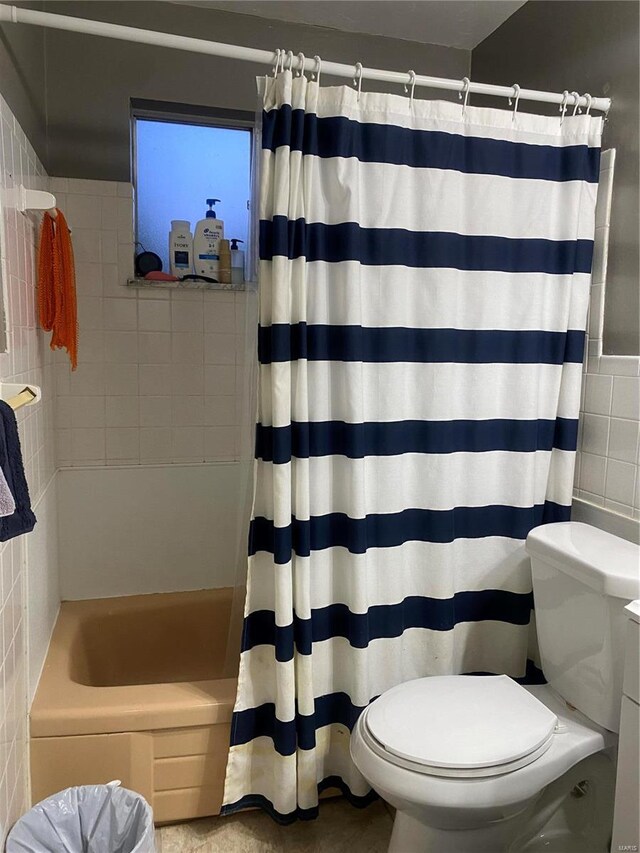 bathroom with toilet, shower / bathtub combination with curtain, and tile walls