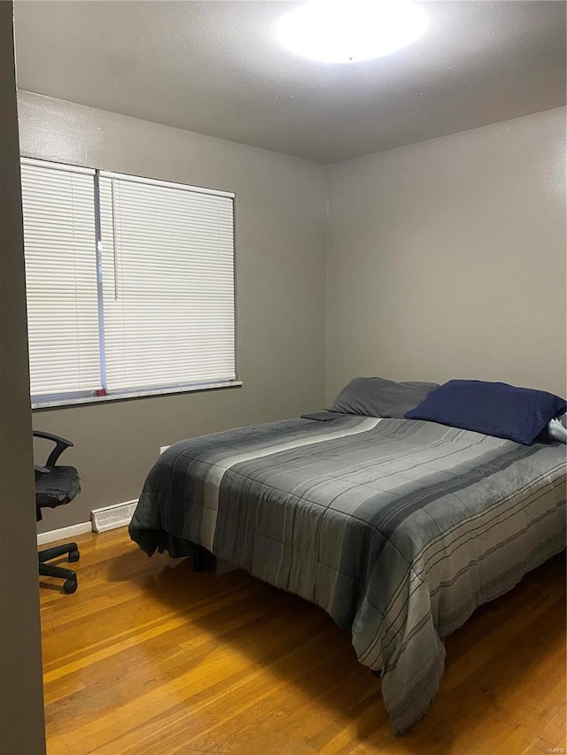 bedroom with hardwood / wood-style floors and a baseboard heating unit