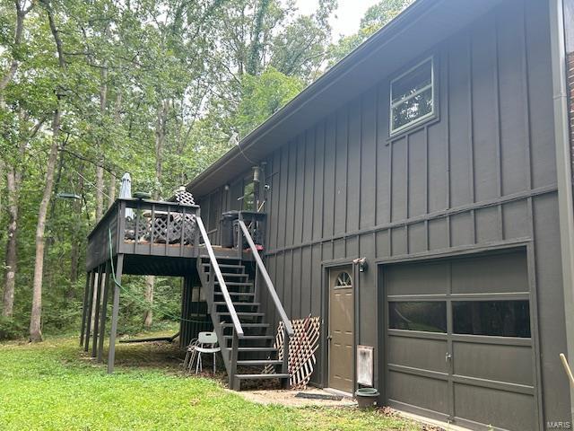 view of side of property featuring a lawn, a garage, and a deck