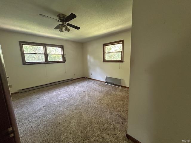 spare room featuring carpet flooring, a healthy amount of sunlight, ceiling fan, and a baseboard radiator