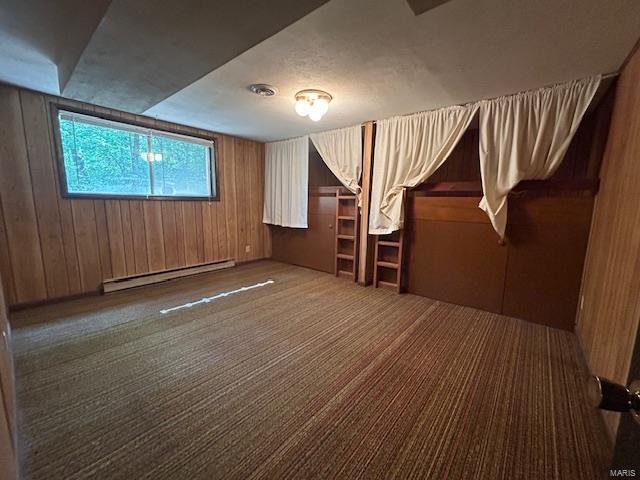 interior space with dark carpet, wooden walls, and a baseboard radiator