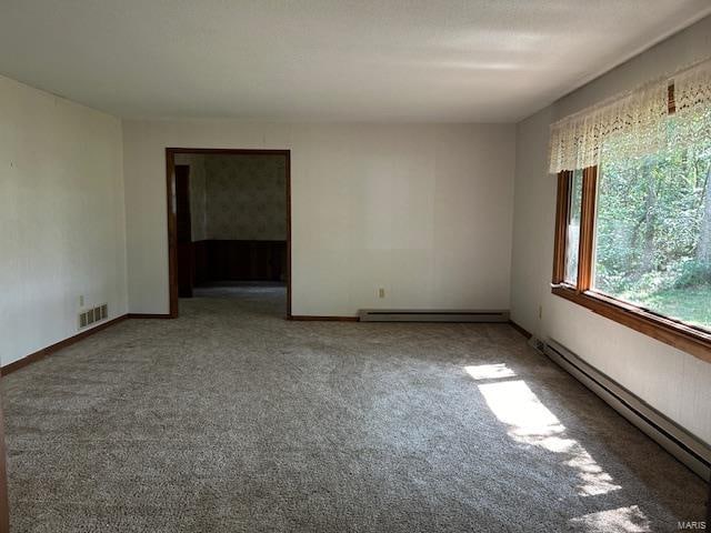 carpeted spare room featuring a baseboard heating unit