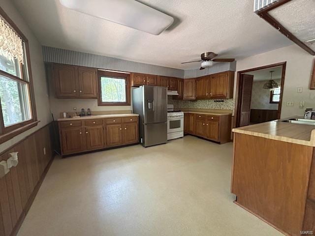 kitchen with stainless steel fridge, white range oven, a healthy amount of sunlight, and sink