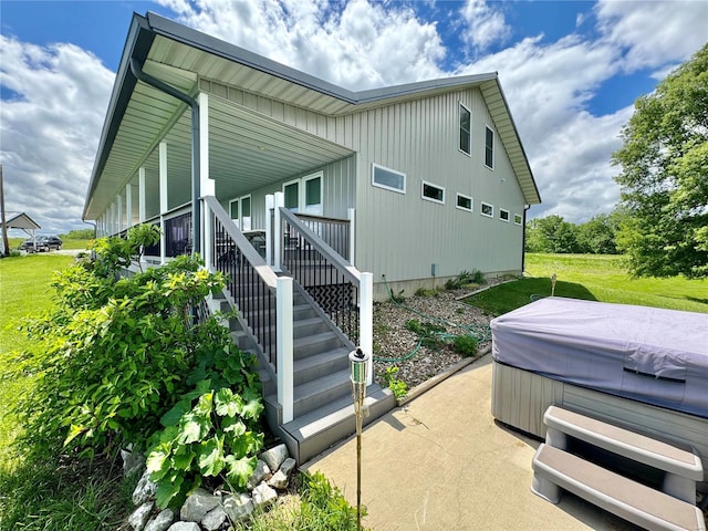 view of side of home with a yard and a hot tub