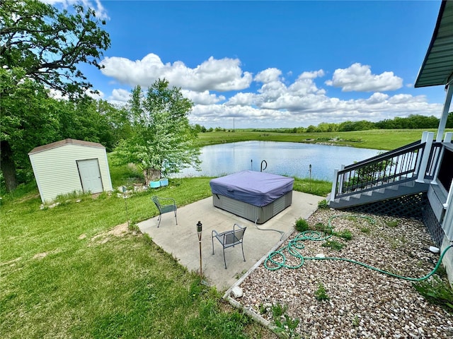 view of yard featuring a deck with water view, a hot tub, and a storage shed