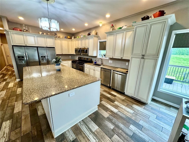 kitchen with stone counters, sink, stainless steel appliances, crown molding, and a chandelier