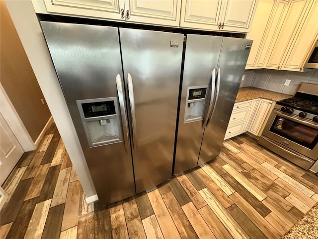 kitchen featuring backsplash, stone counters, light hardwood / wood-style flooring, and stainless steel appliances