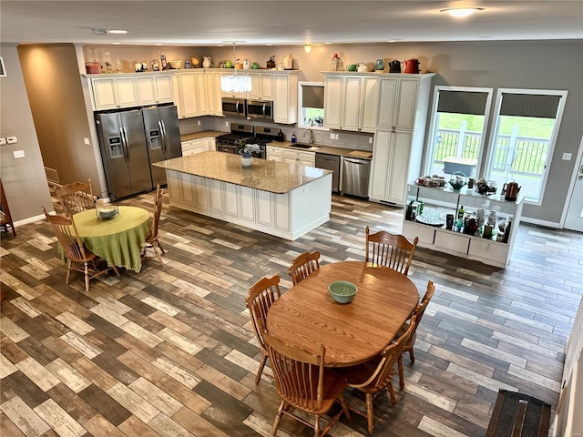 kitchen with hardwood / wood-style floors, a center island, stainless steel appliances, and stone counters