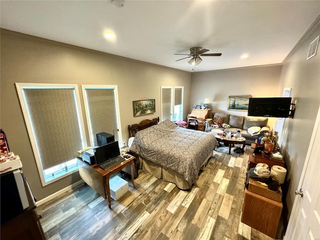 bedroom with hardwood / wood-style flooring, ceiling fan, and ornamental molding