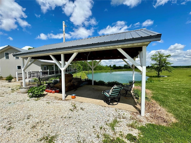 view of vehicle parking with a gazebo, a water view, and a lawn