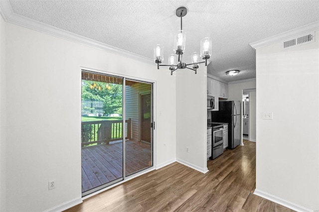 unfurnished dining area featuring a chandelier, a textured ceiling, dark hardwood / wood-style floors, and ornamental molding