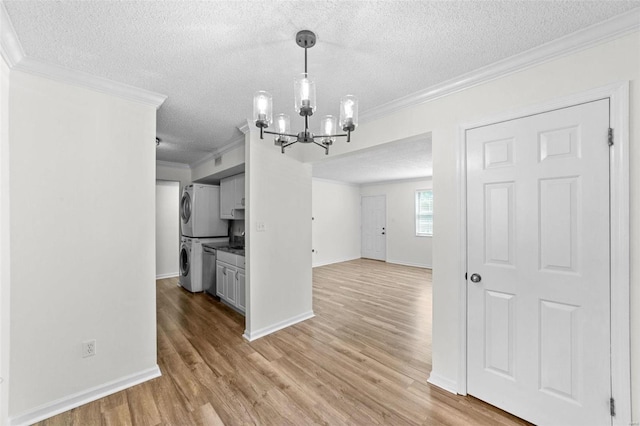 interior space featuring light hardwood / wood-style flooring, a notable chandelier, stacked washer / dryer, crown molding, and a textured ceiling