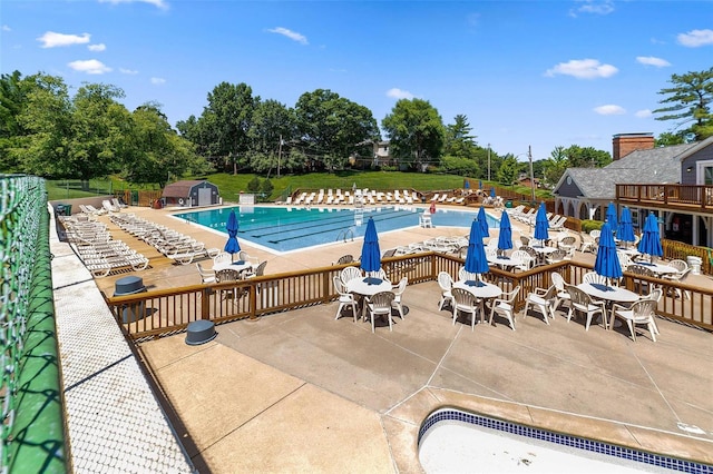 view of pool with a patio area and a shed