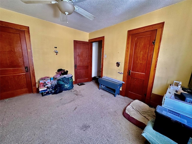 carpeted bedroom featuring ceiling fan and a textured ceiling